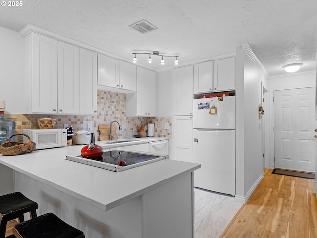 kitchen with kitchen peninsula, white cabinetry, a breakfast bar, and white appliances