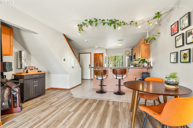 kitchen featuring stainless steel appliances, a breakfast bar, visible vents, light wood-style floors, and a peninsula