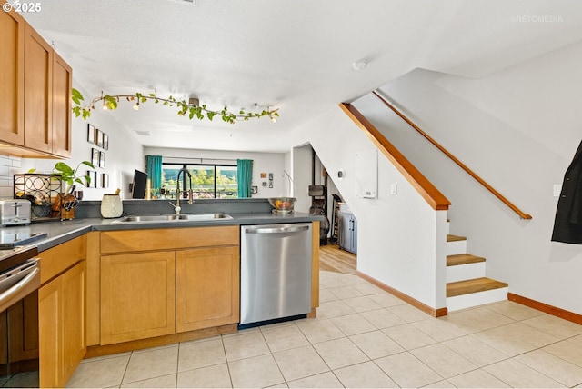 kitchen featuring dark countertops, a sink, dishwasher, baseboards, and stove