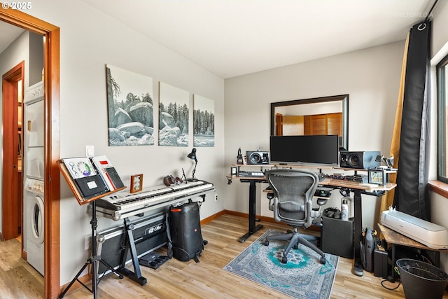 office space featuring baseboards, wood finished floors, and stacked washer and clothes dryer