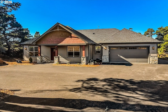 craftsman-style house with driveway, stone siding, a porch, an attached garage, and a shingled roof