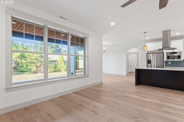 kitchen with hanging light fixtures, stainless steel appliances, light hardwood / wood-style floors, white cabinets, and island exhaust hood