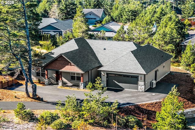 view of front facade with aphalt driveway, stone siding, a shingled roof, and a garage