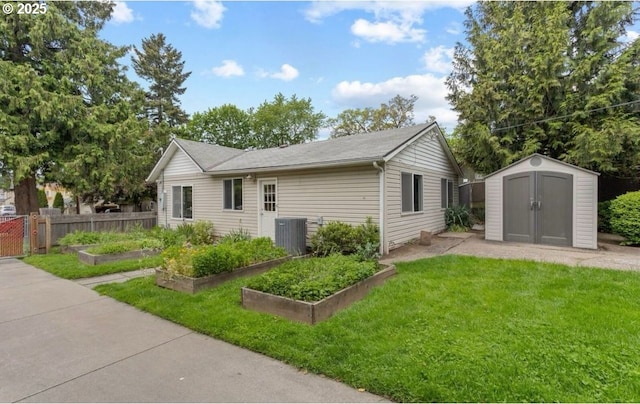 rear view of house featuring fence, a vegetable garden, an outdoor structure, a yard, and a shed
