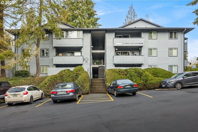 view of building exterior featuring uncovered parking and stairway