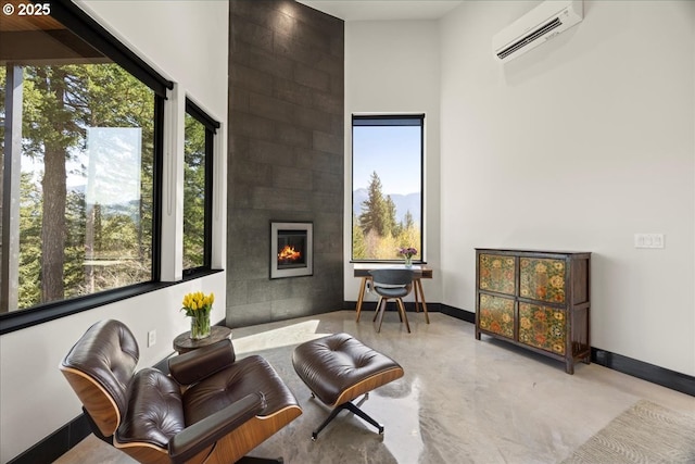 725 NW Angel Heights Rd, Stevenson, WA 98648 - living area featuring baseboards, concrete flooring, a large fireplace, and a wall mounted air conditioner