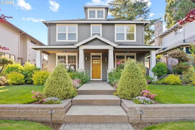 american foursquare style home with a front lawn and covered porch