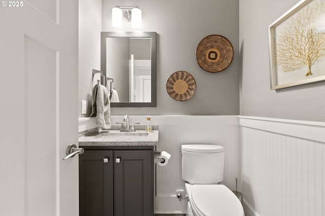 bathroom featuring a wainscoted wall, vanity, and toilet