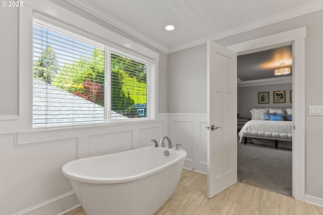 bathroom featuring a decorative wall, ornamental molding, a freestanding tub, wainscoting, and ensuite bathroom