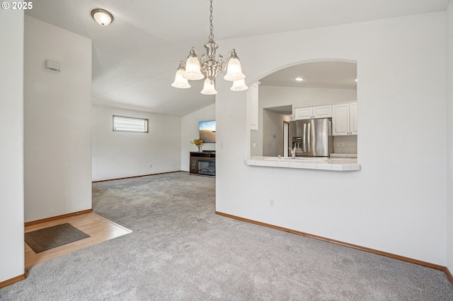 5661 J St, Washougal, WA 98671 - unfurnished living room featuring carpet, vaulted ceiling, a chandelier, arched walkways, and baseboards