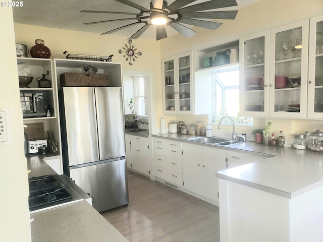 kitchen with stainless steel refrigerator, white cabinetry, plenty of natural light, and sink