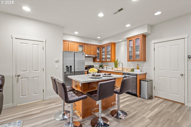 2590 NW 2nd Ter, Gresham, OR 97030 - kitchen with appliances with stainless steel finishes, brown cabinets, a breakfast bar, under cabinet range hood, and recessed lighting