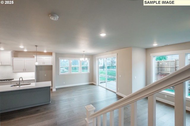 kitchen with a sink, dark wood-style flooring, white cabinetry, light countertops, and baseboards