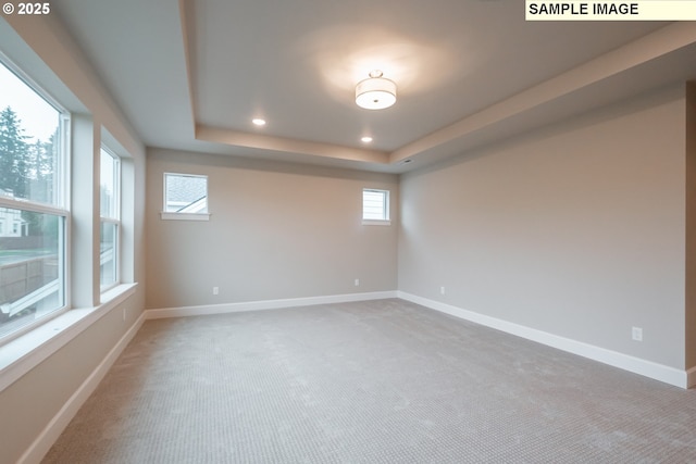 carpeted empty room featuring plenty of natural light, recessed lighting, a raised ceiling, and baseboards