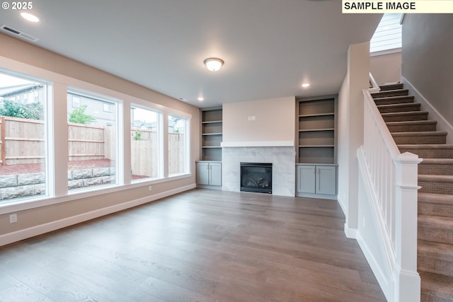 unfurnished living room with wood finished floors, a fireplace, stairway, baseboards, and recessed lighting