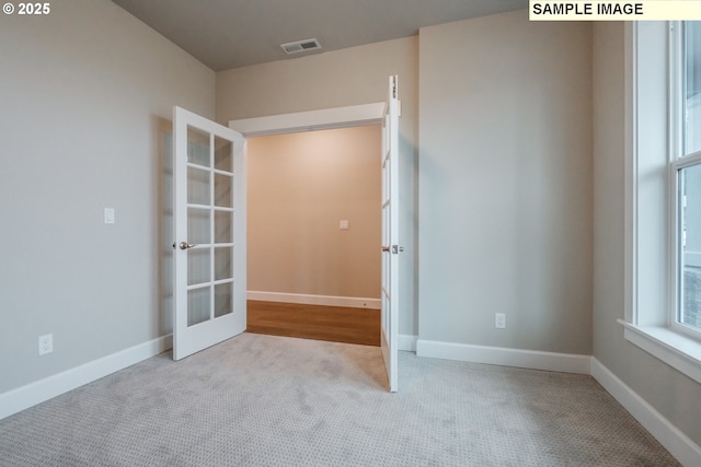carpeted spare room with french doors and baseboards