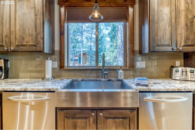 kitchen featuring backsplash, a healthy amount of sunlight, dishwasher, and hanging light fixtures