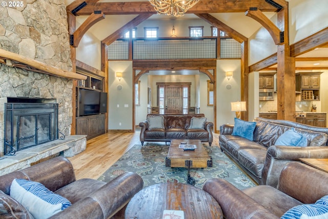 living room with a high ceiling, beam ceiling, a fireplace, and wood-type flooring