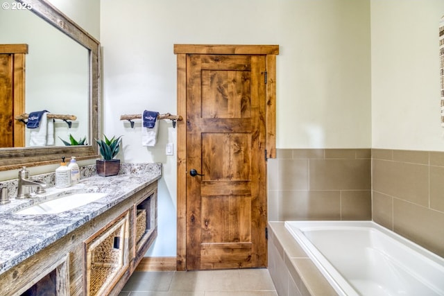 bathroom featuring tile patterned flooring, a relaxing tiled tub, and vanity