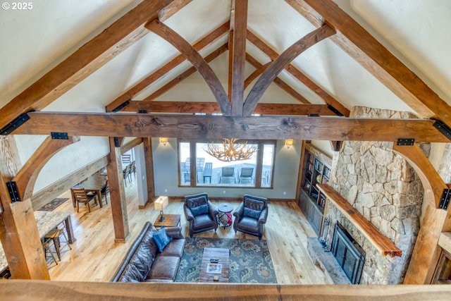 living room featuring a fireplace, a chandelier, light hardwood / wood-style flooring, and beam ceiling