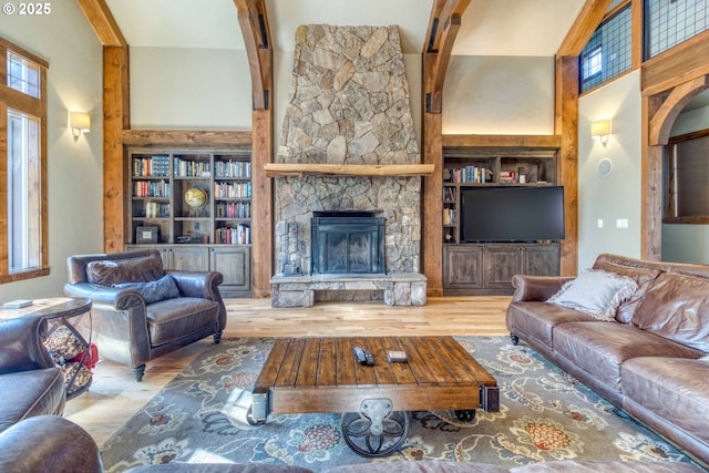 living room with built in shelves, light hardwood / wood-style flooring, a fireplace, and a high ceiling