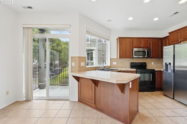 11660 SW Longspur Ter, Beaverton, OR 97007 - kitchen with stainless steel appliances, a sink, a peninsula, decorative backsplash, and recessed lighting