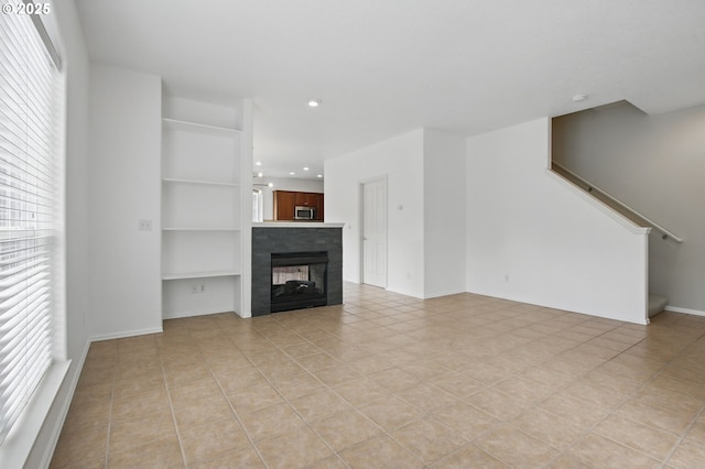 11660 SW Longspur Ter, Beaverton, OR 97007 - unfurnished living room featuring light tile patterned flooring, built in features, stairway, recessed lighting, and a tiled fireplace