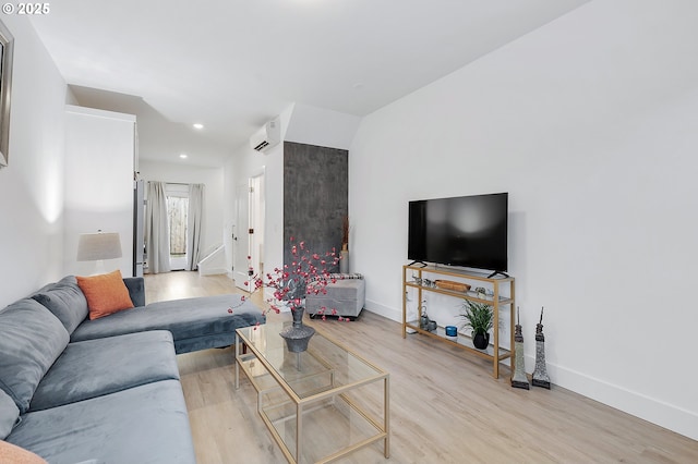 living room featuring a wall mounted air conditioner and light hardwood / wood-style flooring