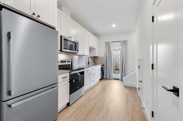 kitchen with white cabinets, sink, light wood-type flooring, and stainless steel appliances