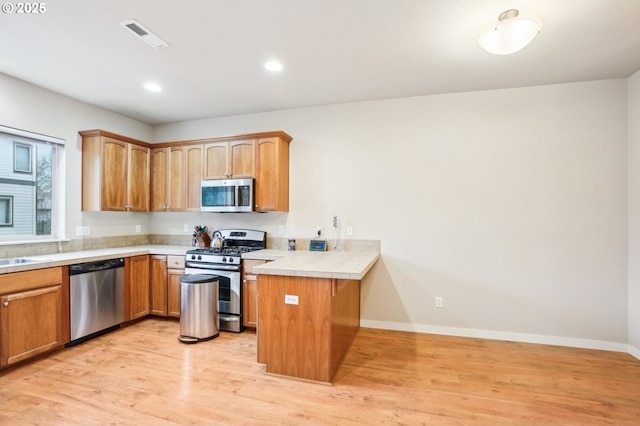 kitchen featuring sink, stainless steel appliances, light hardwood / wood-style flooring, and kitchen peninsula