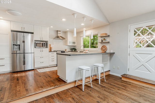 1505 NW 118th Ct, Portland, OR 97229 - kitchen featuring stainless steel appliances, wall chimney range hood, dark wood finished floors, a peninsula, and lofted ceiling