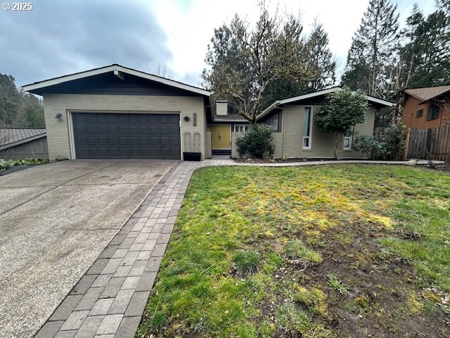 ranch-style home with concrete driveway, an attached garage, fence, and a front yard