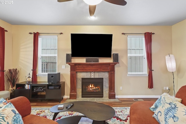 living room featuring ceiling fan, hardwood / wood-style floors, and a tiled fireplace