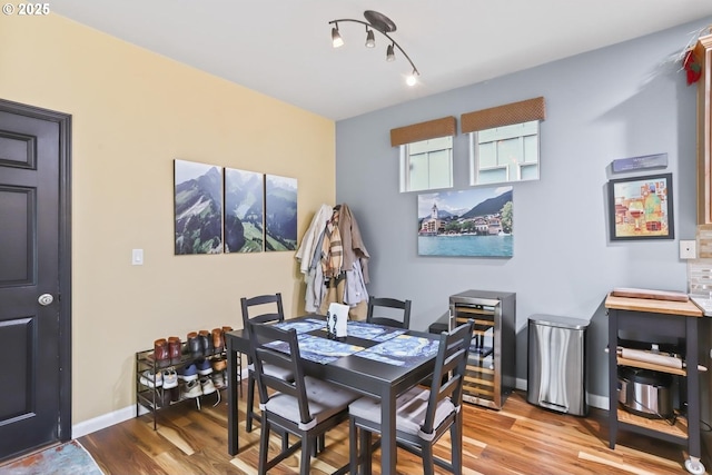 dining space featuring rail lighting, light wood-type flooring, and beverage cooler