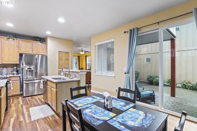 dining room with sink, ceiling fan, a healthy amount of sunlight, and light hardwood / wood-style flooring