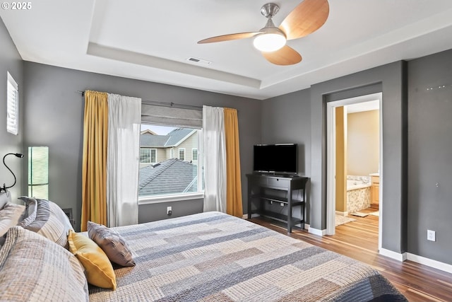 bedroom with multiple windows, a tray ceiling, and ceiling fan