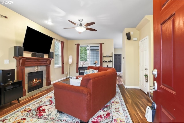 living room with ceiling fan, dark wood-type flooring, and a tiled fireplace