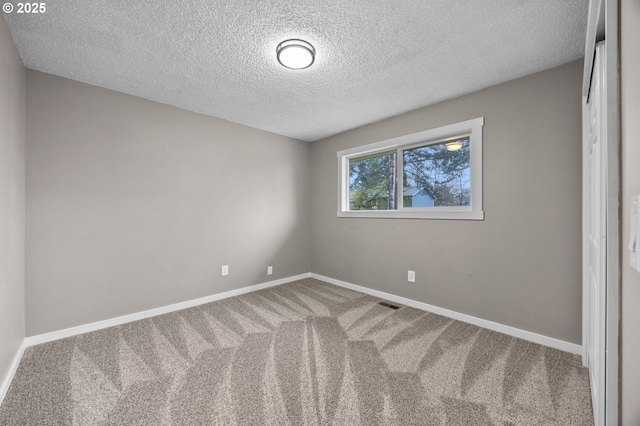 spare room with visible vents, carpet, baseboards, and a textured ceiling