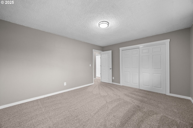 unfurnished bedroom featuring a textured ceiling, carpet, a closet, and baseboards