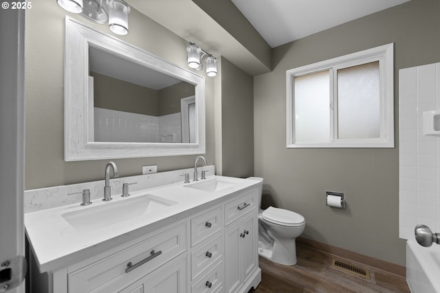 full bath with double vanity, visible vents, wood finished floors, and a sink