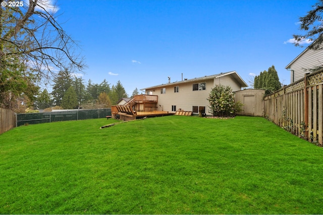 view of yard with an outbuilding, a fenced backyard, and a wooden deck