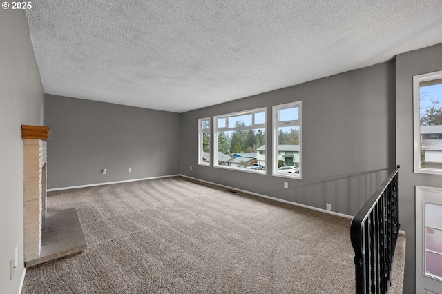 unfurnished living room featuring baseboards, a textured ceiling, a brick fireplace, and carpet flooring