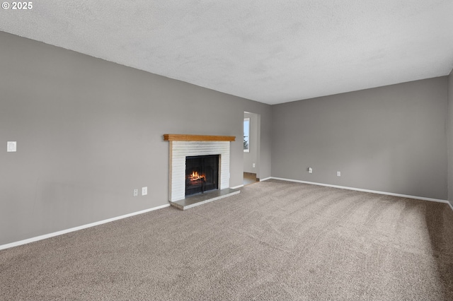 unfurnished living room with a brick fireplace, a textured ceiling, baseboards, and carpet floors