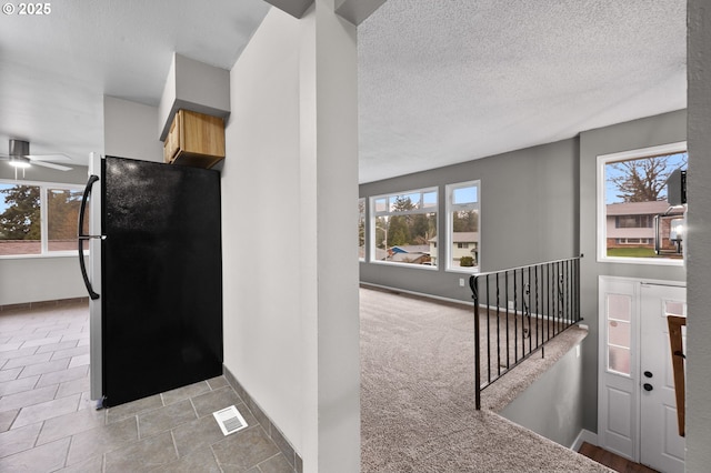 kitchen with visible vents, a textured ceiling, freestanding refrigerator, and baseboards