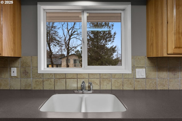 kitchen with dark countertops, a healthy amount of sunlight, tasteful backsplash, and a sink