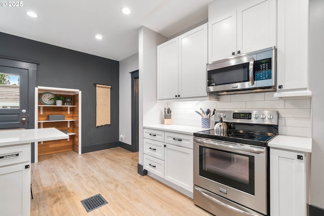 kitchen featuring decorative backsplash, appliances with stainless steel finishes, light hardwood / wood-style flooring, and white cabinetry