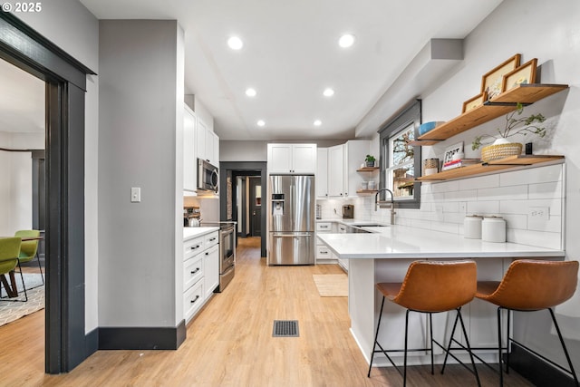 kitchen featuring sink, stainless steel appliances, backsplash, a kitchen bar, and white cabinets