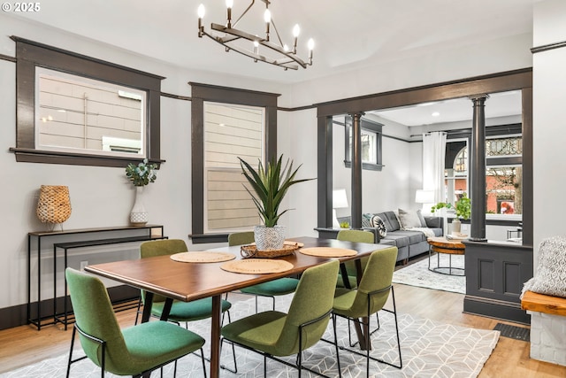 dining space featuring a chandelier, light hardwood / wood-style floors, and decorative columns