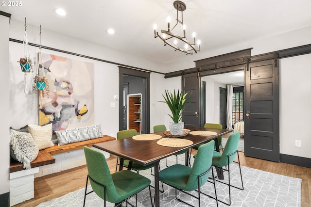 dining room featuring a chandelier, a barn door, and light hardwood / wood-style floors