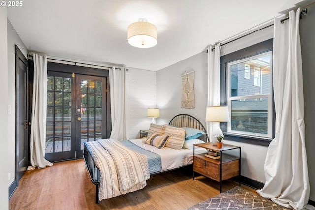 bedroom featuring wood-type flooring, access to outside, and french doors